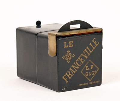 une vieille boîte noire munie d'une poignée, posée sur une surface blanche