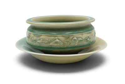 a green bowl and saucer on a white plate