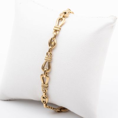 a close up of a gold chain bracelet on a pillow