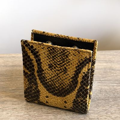a close up of a snake skin wallet on a wooden table