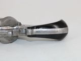 a metal object with a black handle on a white surface