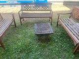 trois bancs en bois et une petite table dans l'herbe