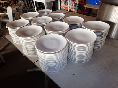 beaucoup d'assiettes blanches posées sur une table dans une pièce