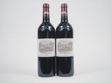 two bottles of red wine sitting next to each other on a white surface