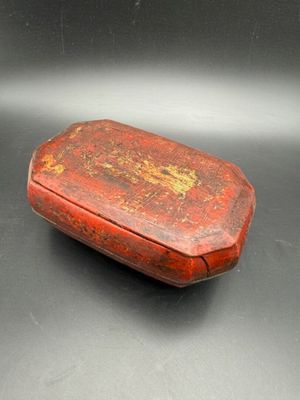 an old red box sitting on top of a black table