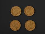 four gold sovereigns on a black surface with a black background