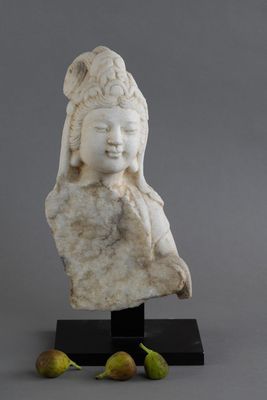 une statue en marbre blanc représentant une femme coiffée d'un chapeau, avec deux figurines à côté