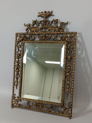 un miroir au cadre doré ouvragé accroché à un mur blanc dans une pièce