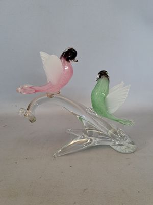 two glass birds sitting on top of a glass branch