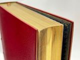an open red book sitting on top of a table next to a white background