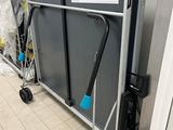 un présentoir métallique muni d'une poignée et de deux roulettes, dans une pièce