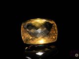 a close up of a yellow and black diamond on a black surface
