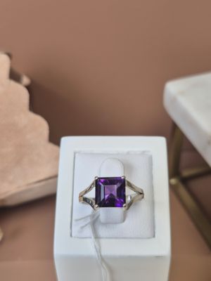 une bague sertie d'une pierre violette, posée sur une table
