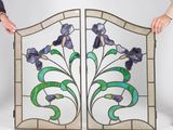 two people holding up stained glass panels with flowers on them