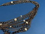 a close up of a necklace with pearls on it