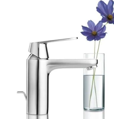 un vase contenant une fleur, à côté d'un robinet