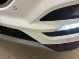the front end of a white car with a blue light on