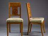 two wooden chairs with upholstered upholstered backs and a carved back