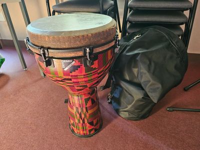a drum sitting next to a bag on the floor