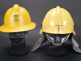pair of yellow fire helmets on display against a black background