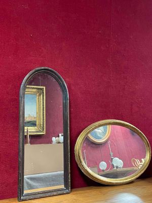 three mirrors sitting on a wooden shelf next to a red wall