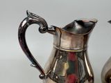 a silver pitcher and a silver pitcher on a table