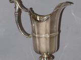 an antique silver plated pitcher on a pedestal with a handle
