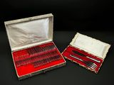 des couverts dans un coffret en argent doublé de velours rouge, posé sur un fond noir