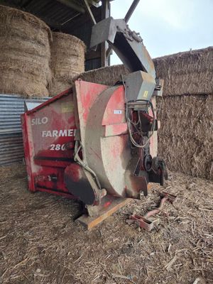 un tracteur rouge qui se trouve dans le foin