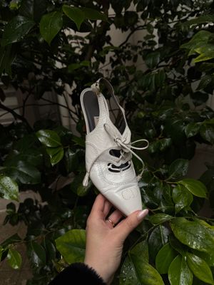 une personne tenant une paire de chaussures blanches devant un arbre