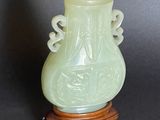 a green vase sitting on a wooden stand on a black surface