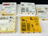quatre boîtes contenant un assortiment de composants électroniques, posées sur une table