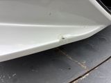 the front bumper of a white car with a hole in it