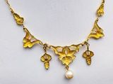 a gold necklace with leaves and pearls on a mannequin