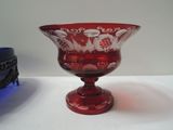 a red glass bowl sitting on a table next to a blue bowl