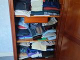 une armoire en bois remplie de nombreux vêtements dans une pièce