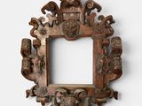 an old wooden frame with carvings on it against a white wall