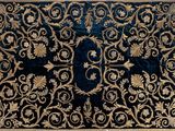 a close up of a blue and gold rug on a white surface
