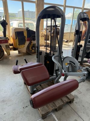 an image of a gym room filled with equipment and a man working on a machine