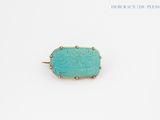 a turquoise stone ring with gold accents on a white surface