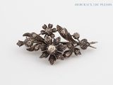an image of a silver broochle with flowers and leaves