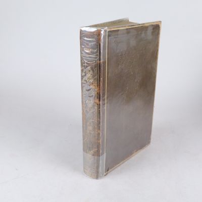 un vieux livre posé sur une table à côté d'un mur blanc