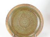 a brown plate with a green rim sitting on a white surface