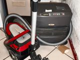un aspirateur posé par terre à côté d'une valise