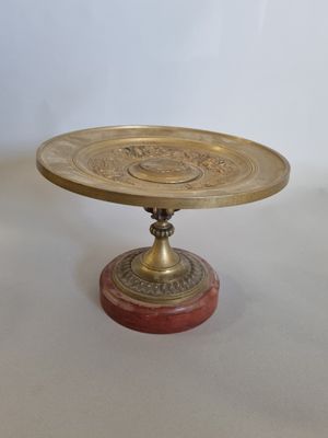 une assiette dorée avec un fond rouge posée sur une table blanche