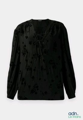 Le chemisier est noir et orné de fleurs noires.