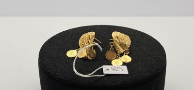 un gros plan sur une paire de boucles d'oreilles posées sur une boîte noire