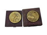 two gold medals with a woman and a man on them