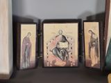 three framed pictures of saints on a shelf next to a book