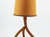 La lampe est fabriquée en corde et possède un abat-jour marron.